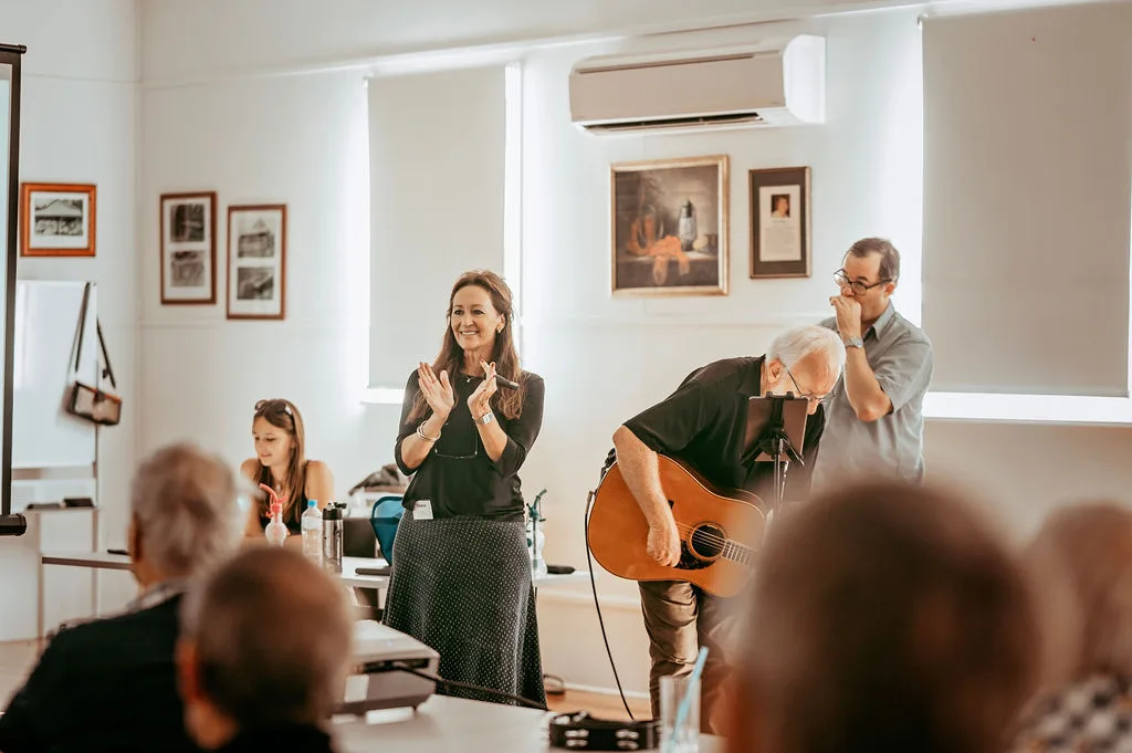 A group of older adults singing together joyfully in a community hall
